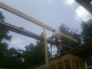 Carpenter setting a ridge beam over a new addition frame — Ice Dam Removal by Roofing Brothers in Clendenin