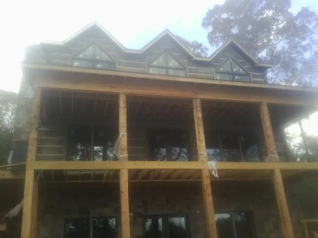 Dormers and porch framing on a large log home under construction — Roof Coating work by our crew in Clendenin