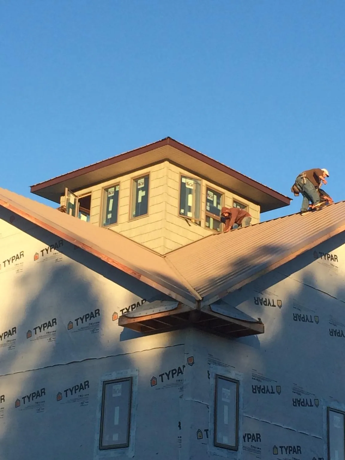 Roofers working around a rooftop cupola on a new metal roof at sunset — Roof Waterproofing in Clendenin by Roofing Brothers